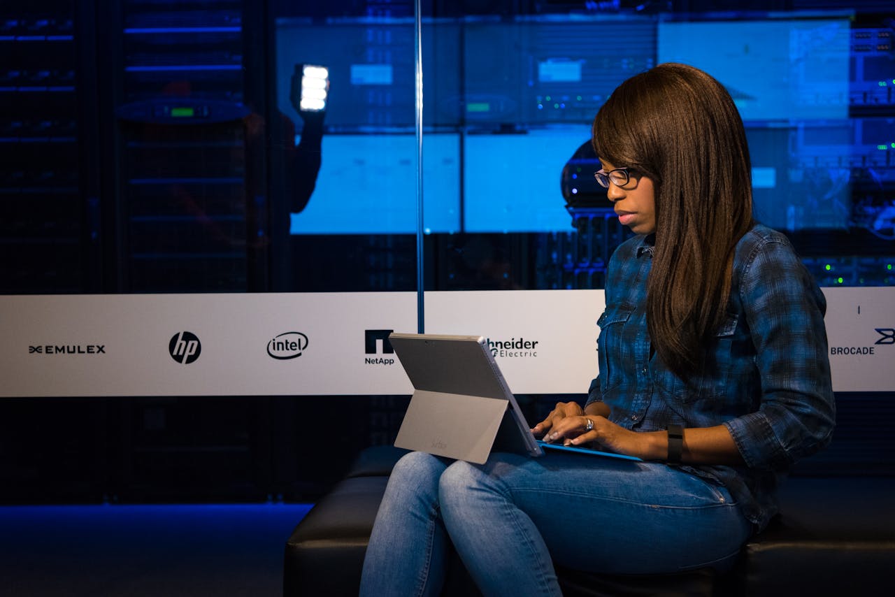 pexels-photo-1181319 Professional woman working on laptop in a server room, showcasing technology and remote work.